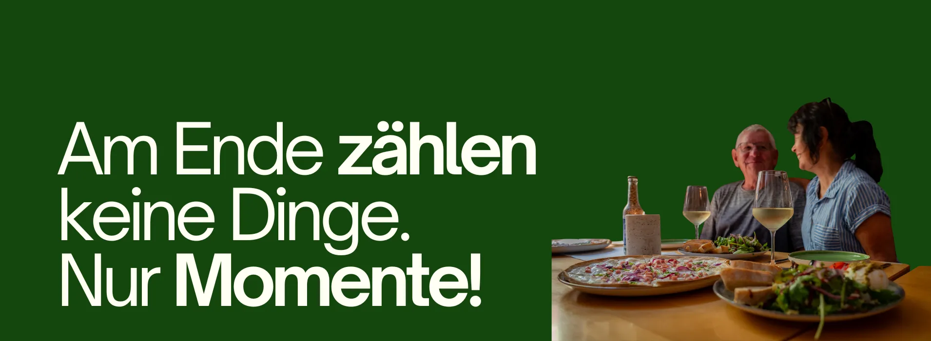 Zwei Personen sitzen an einem Tisch und essen gemeinsam Pizza, Salat und Brot; auf dem Tisch stehen Weißwein und eine Flasche; links der Text ‚Am Ende zählen keine Dinge. Nur Momente!‘ vor dunkelgrünem Hintergrund.